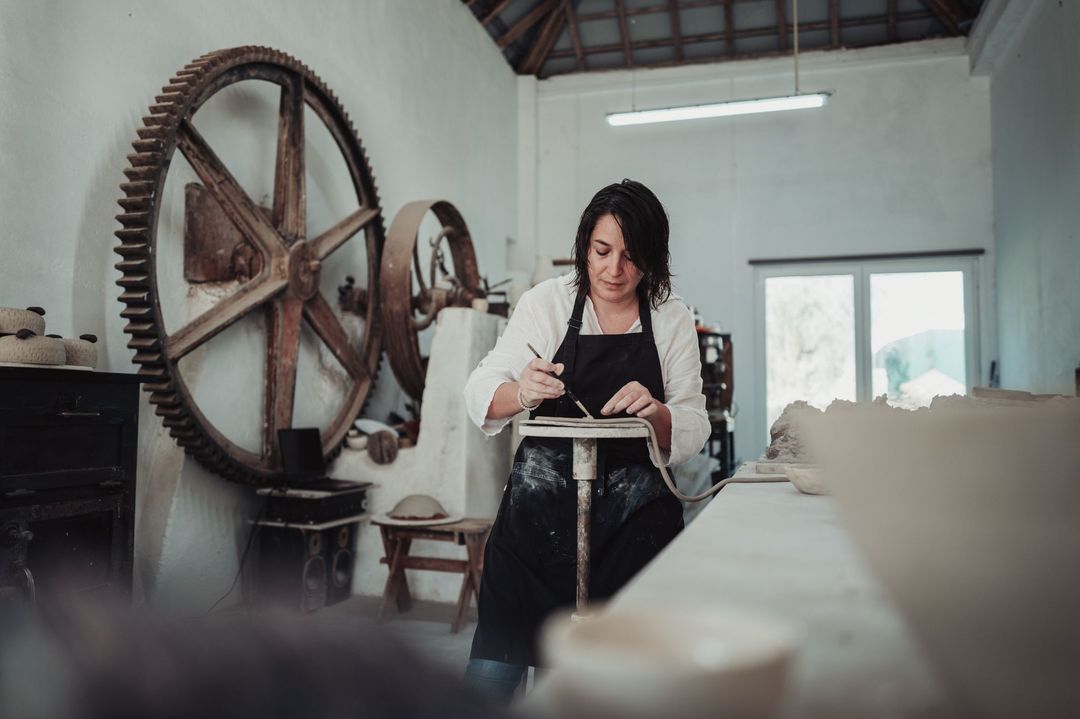 Diana working on a piece on a modelling stand, with a tool in her hand