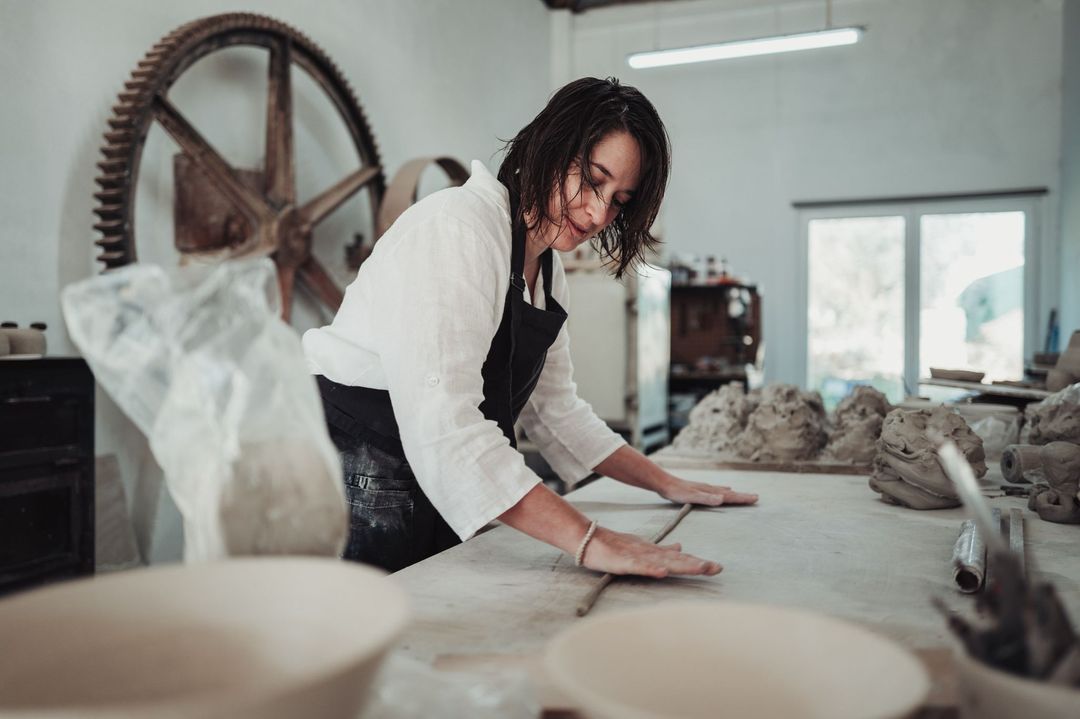 Diana leaning over the long work table, preparing clay