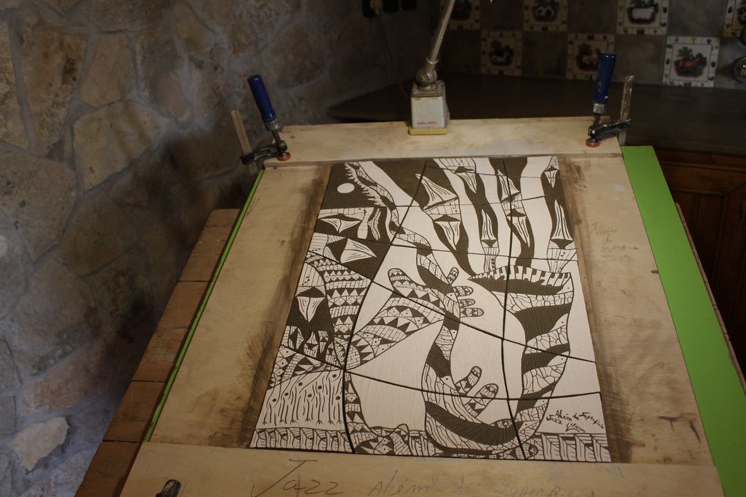 Clay panel in a wooden frame, half scratched with a black and white drawing of figures