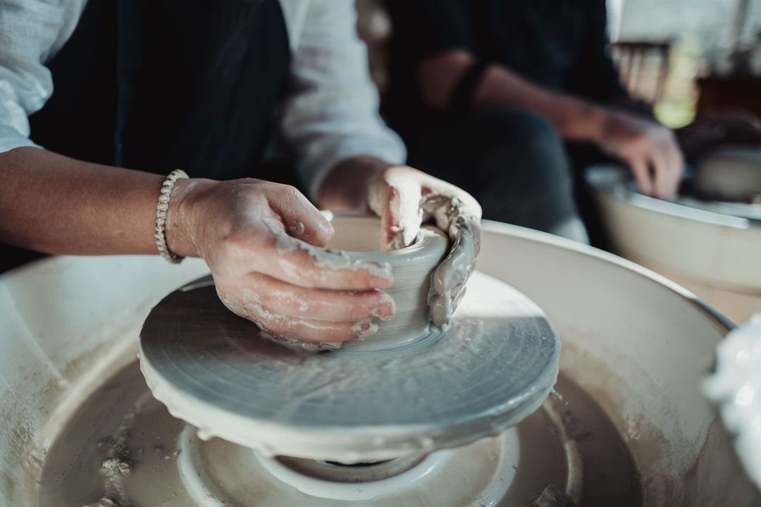 Close-up of hands shaping a small bowl on the wheel