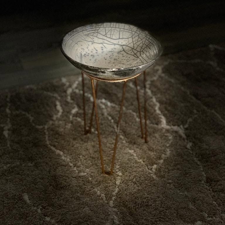 White crackled raku bowl resting on a thin copper-coloured metal stand