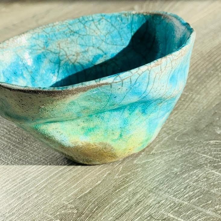 Irregular raku bowl with a turquoise glaze full of fine dark cracks