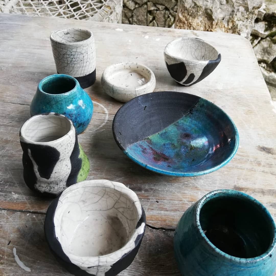 Cups, bowls and a plate on a stone table, some turquoise, some white with black smoke marks