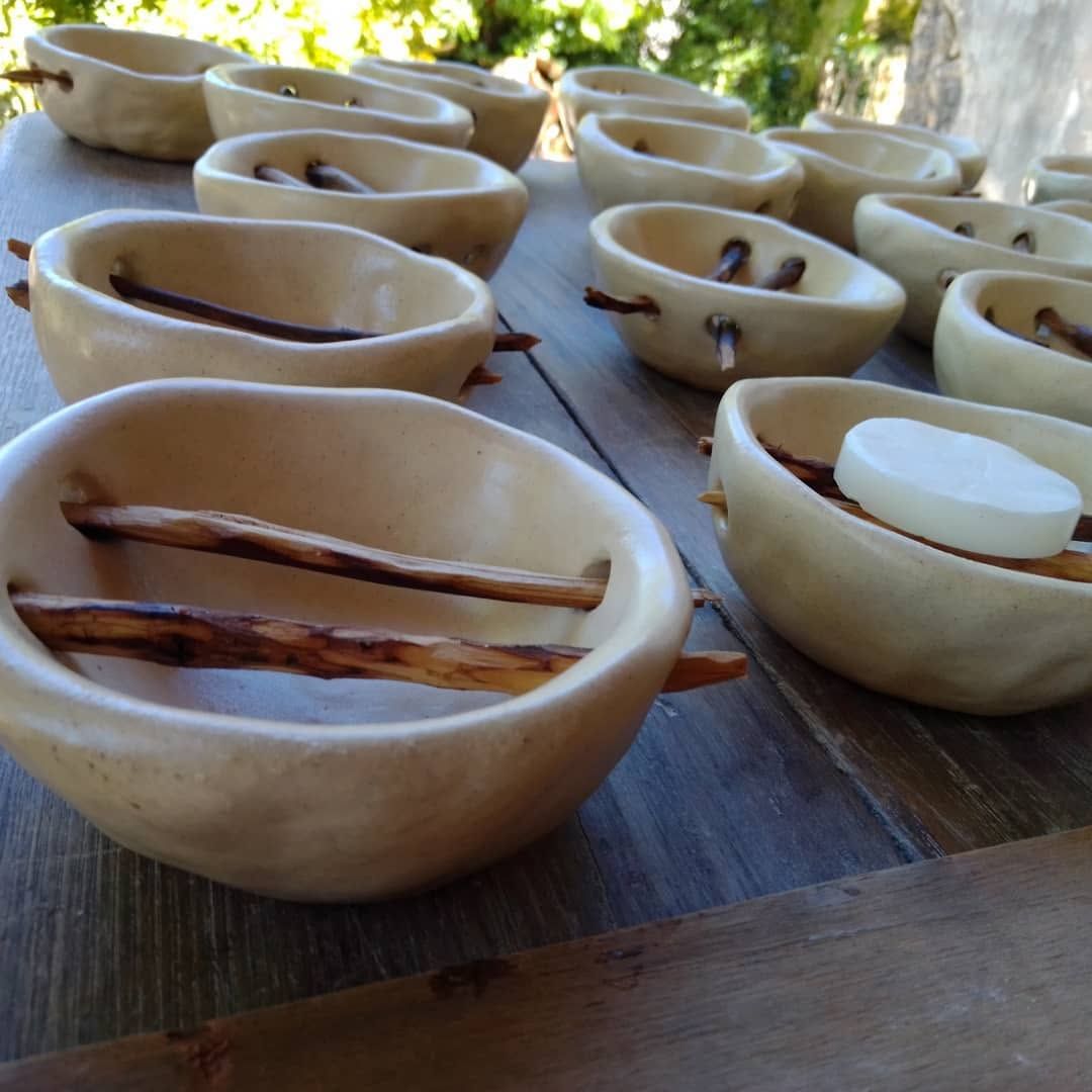 Rows of pale, irregular soap dishes, each with a small twig and a round bar of soap